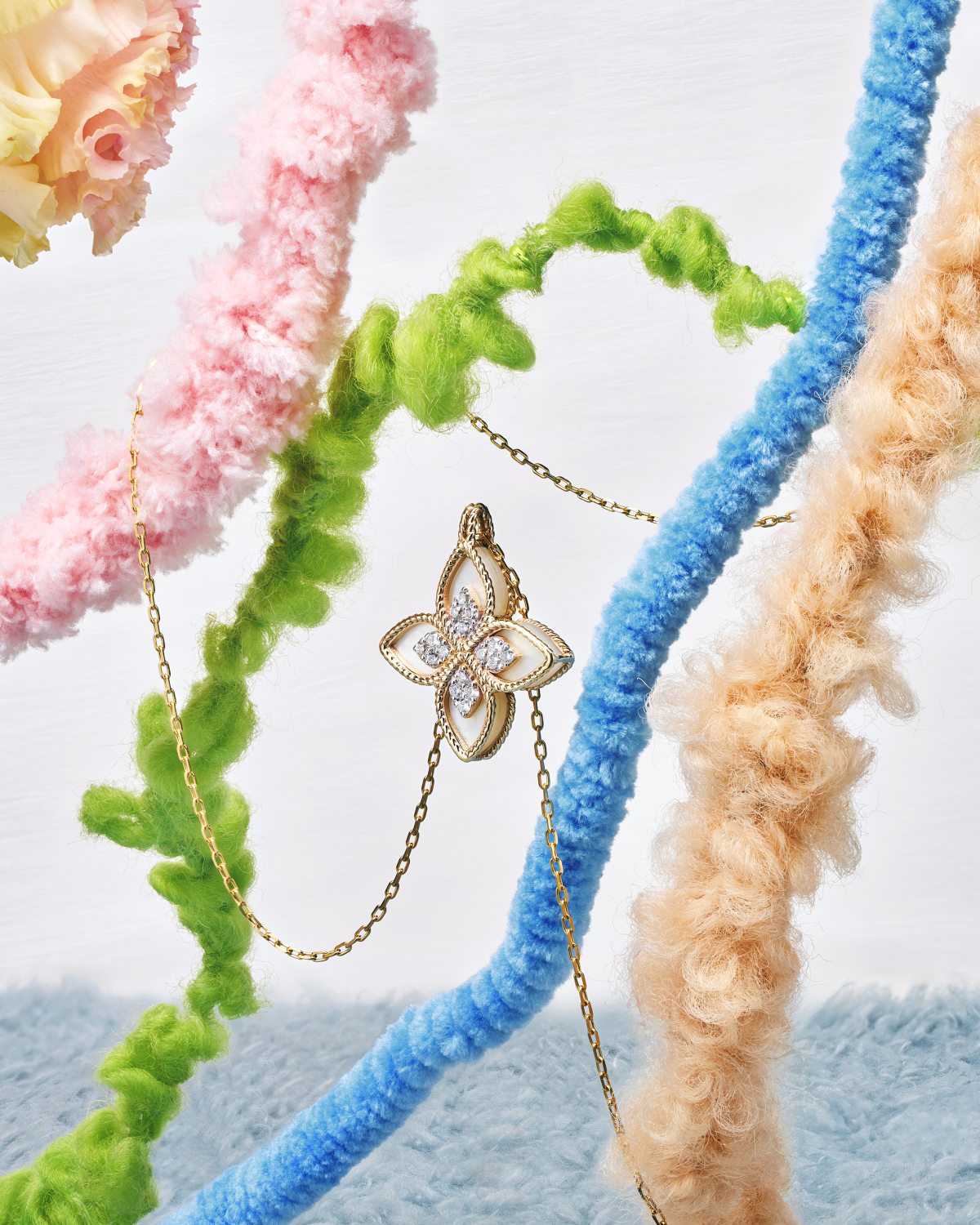 Gold pendant necklace with an openwork floral motif among colorful textured stems.