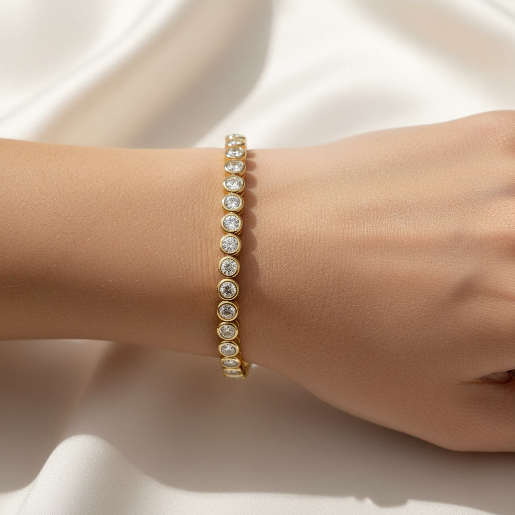 Bezel-set diamond tennis bracelet worn on a wrist.