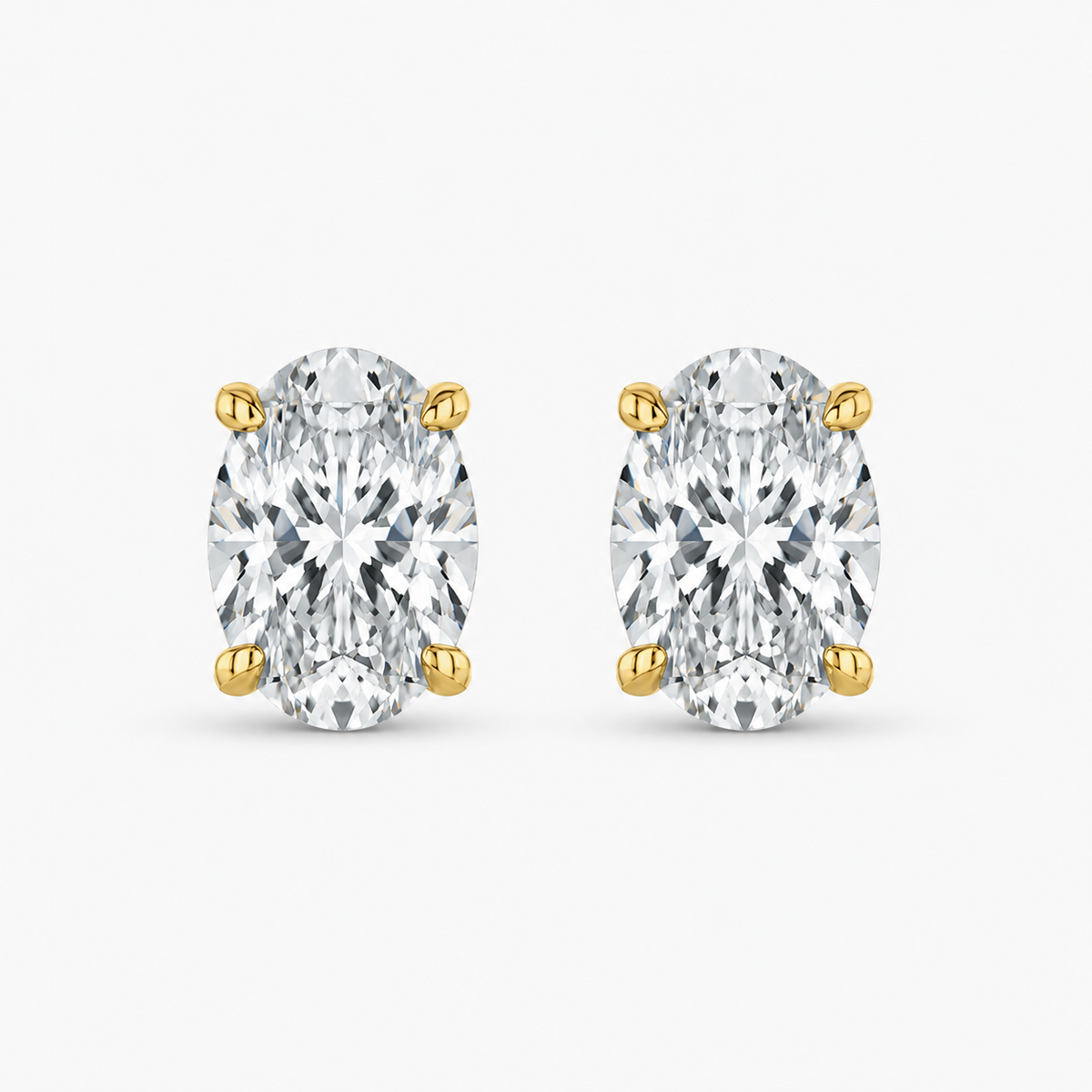 Pair of oval-cut diamond stud earrings with yellow gold prongs, front view.
