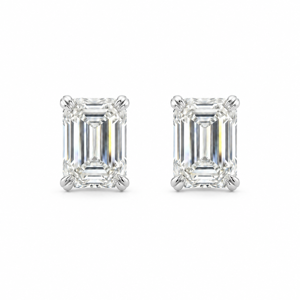 Pair of emerald-cut diamond stud earrings in white metal, front view.
